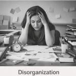 Person overwhelmed by cluttered workspace.