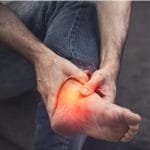 Person holding painful ankle area